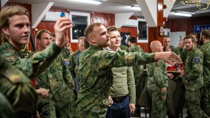 2 militairen in uniform gooien ongeveer tegelijkertijd een dartpijltje het beeld uit.