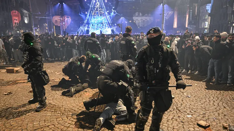 Voertuigen van de ME en politie met mannen met schilden ervoor.