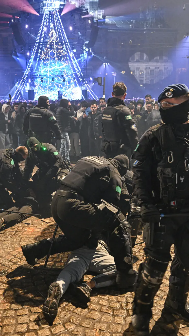 Voertuigen van de ME en politie met mannen met schilden ervoor.