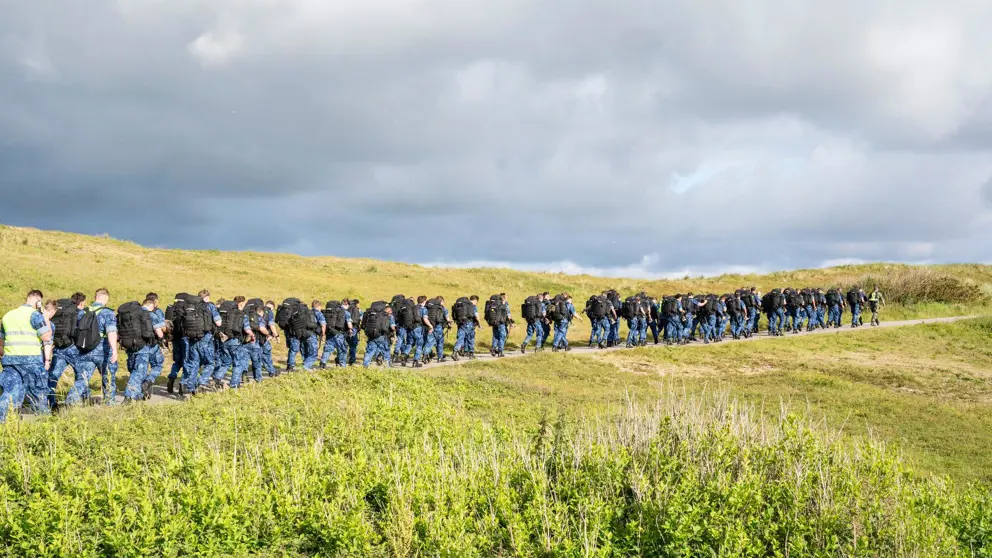 Archieffoto van dienjaarmilitairen die door natuurgebied lopen.