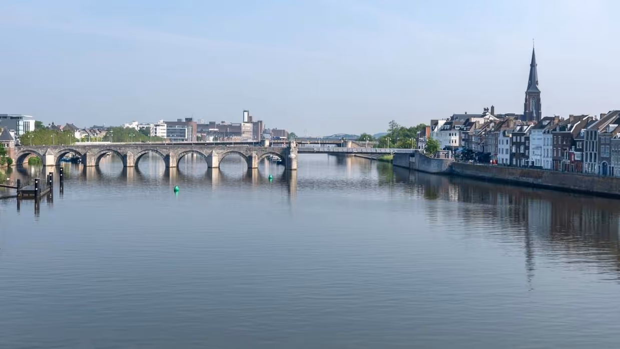 Rivier de Maas stroomt onder oude brug in Maastricht.