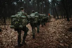 Reservisten lopen met bepakking door een bos.