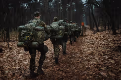 Reservisten lopen met bepakking door een bos.