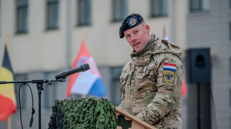 Militair in uniform houdt toespraak vanachter katheder.
