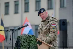 Militair in uniform houdt toespraak achter katheder.