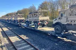 Legervoertuigen staan op treinstel achter elkaar opgesteld om per spoor te worden vervoerd.