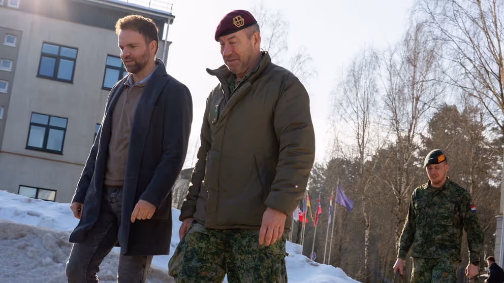 Staatssecretaris Derk Boswijk loopt naast een militair. Op de grond ligt sneeuw.