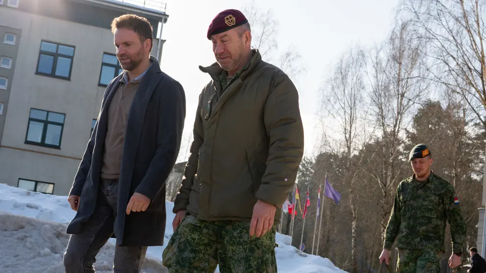 Staatssecretaris Derk Boswijk loopt naast een militair. Op de grond ligt sneeuw.