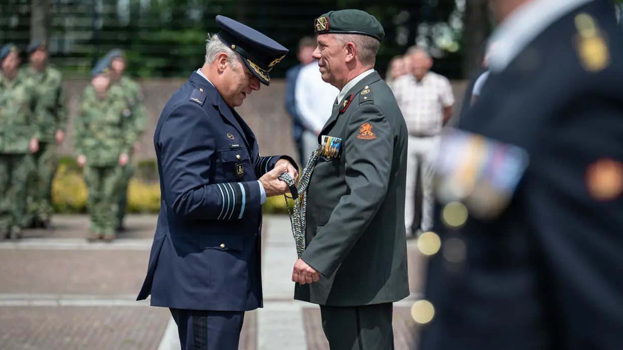 Commandant der Strijdkrachten tegenover adjudant Cees Bielander op een plein met daar omheen militairen en burgers die toekijken.