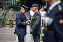 Een militair hangt een andere militair iets om.