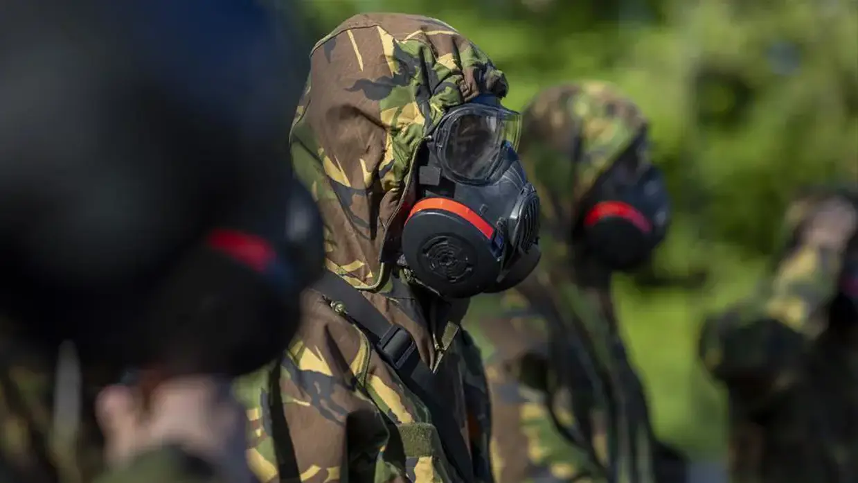 Een deelnemer aan de oefening met een gasmasker op het gezicht.