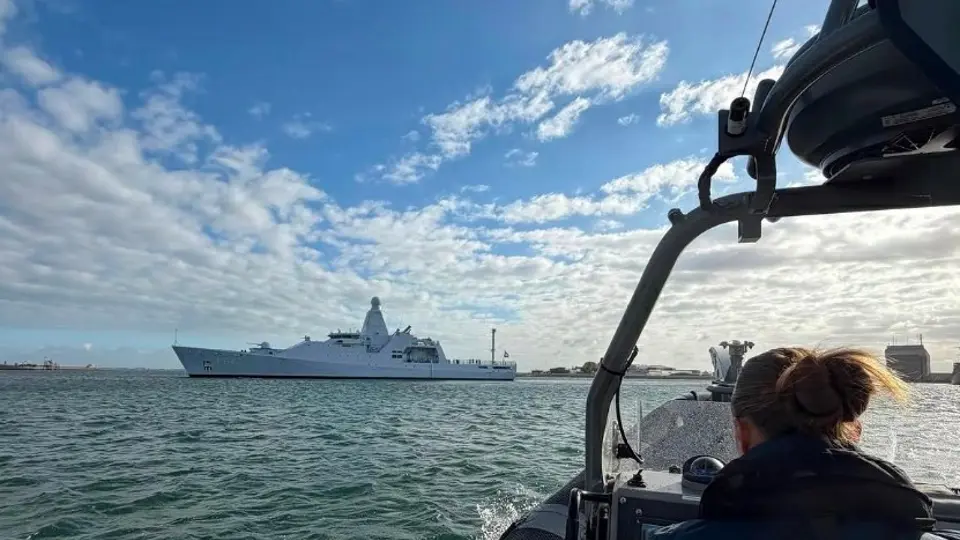 Een marechaussee in een boot vaart richting een schip