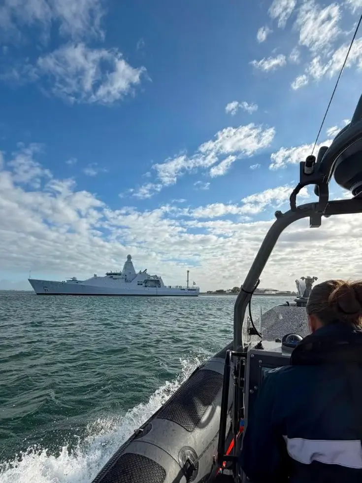 Een marechaussee in een boot vaart richting een schip