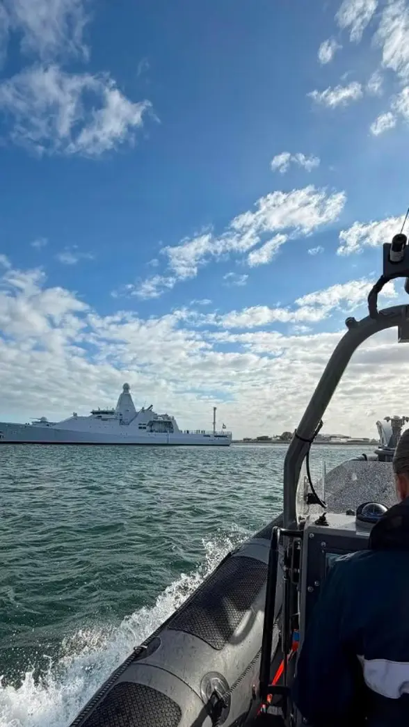Een marechaussee in een boot vaart richting een schip