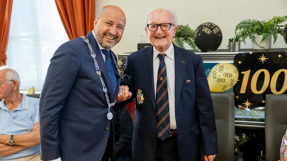 Burgmeester met ambtsketen staat naast 100-jarige veteraan.