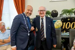 Burgmeester met ambtsketen staat naast 100-jarige veteraan.
