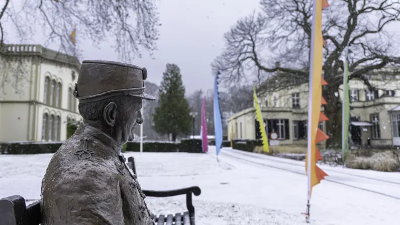 Bronbeker in de sneeuw, een bronzen beeld die een veteraan representeertop een bankje in het landgoed. 