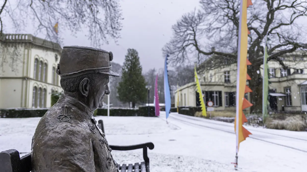 Bronbeker in de sneeuw, een bronzen beeld die een veteraan representeertop een bankje in het landgoed. 
