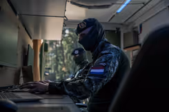 Onherkenbare militair zit achter een computer.