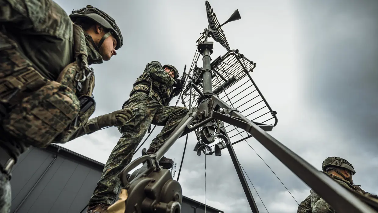 2 militairen aan het werk aan een schotelantenne.