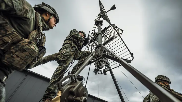 2 militairen aan het werk aan een schotelantenne.