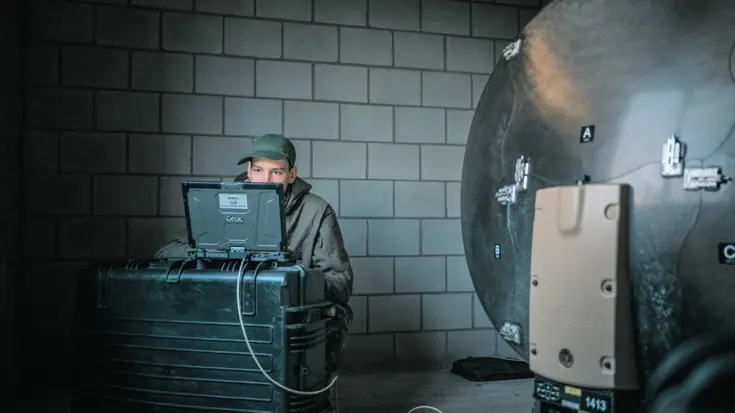 Militair zittend in een donkere ruimte achter een computer.