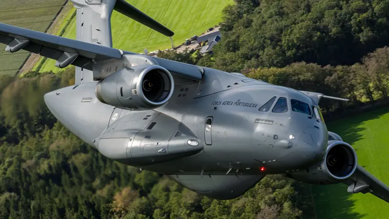 Een C-390 vliegende boven Nederlandse weilanden.
