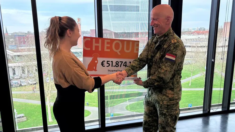 Militair overhandigt cheque van 51.874 euro aan vrouw.