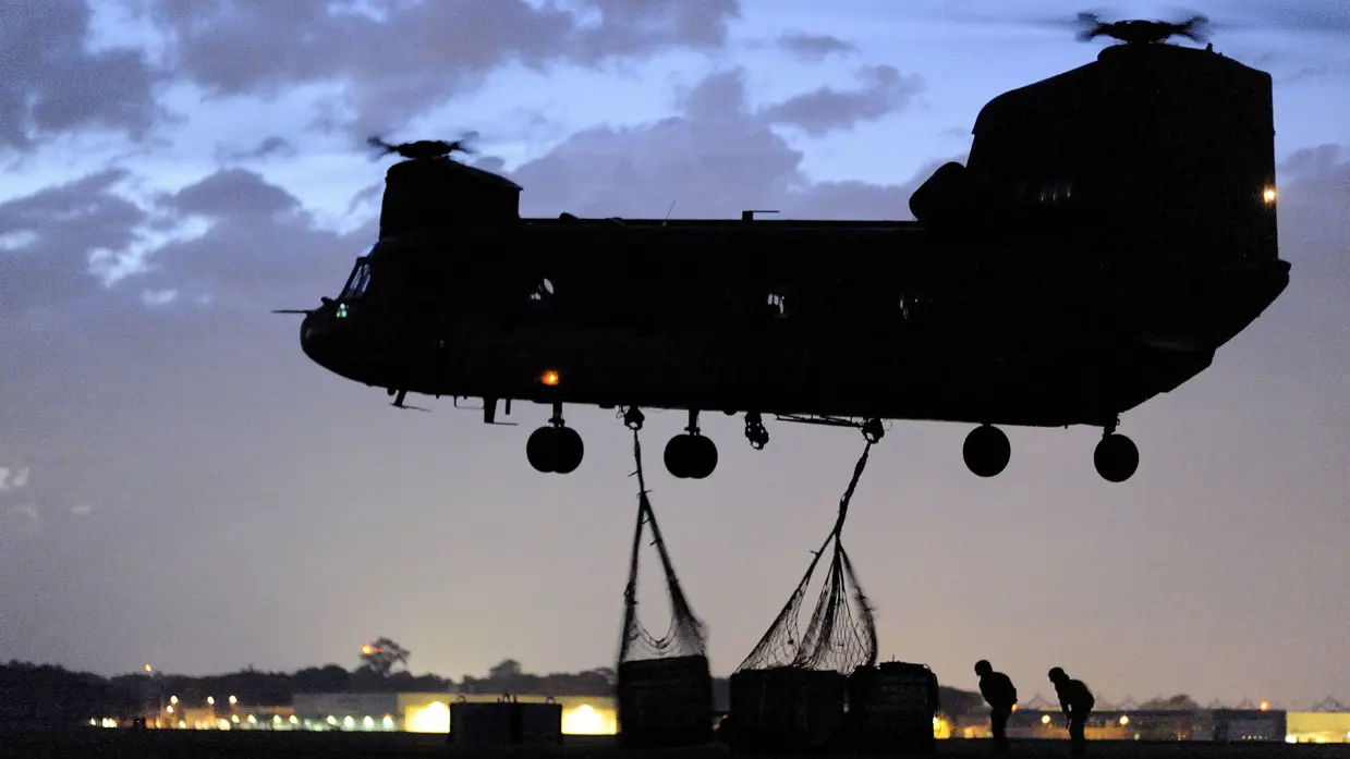 Een Chinook-transporthelikopter vervoert tijdens een nachtvlucht goederen.