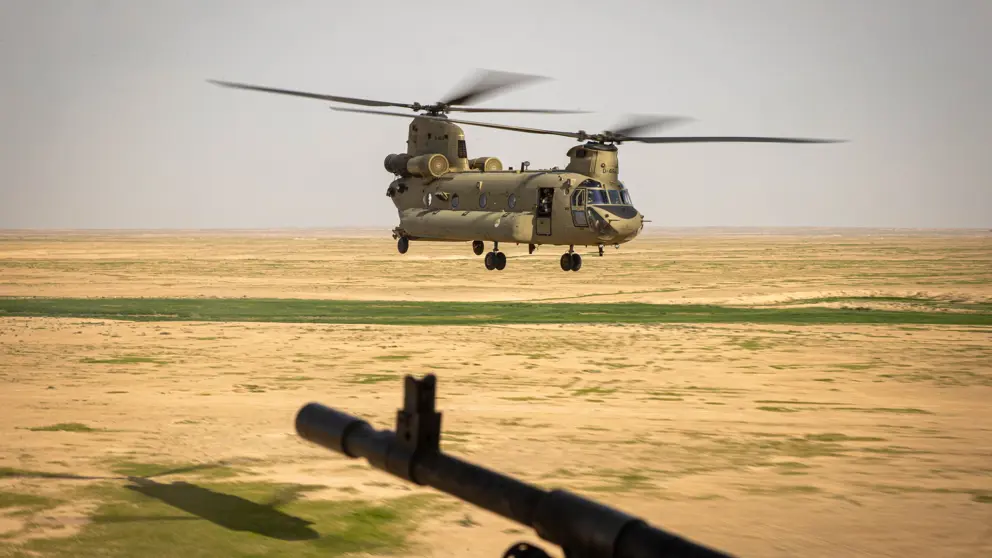 Chinook-transporthelikopter vlak boven de grond in woestijngebied. 