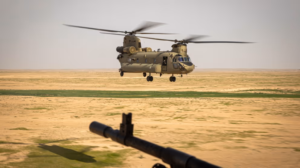 Chinook-transporthelikopter vlak boven de grond in woestijngebied. 