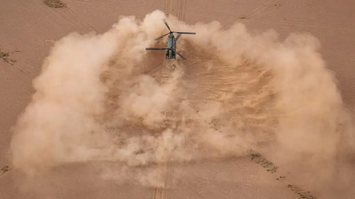 Een helikopter landt in de woestijn.