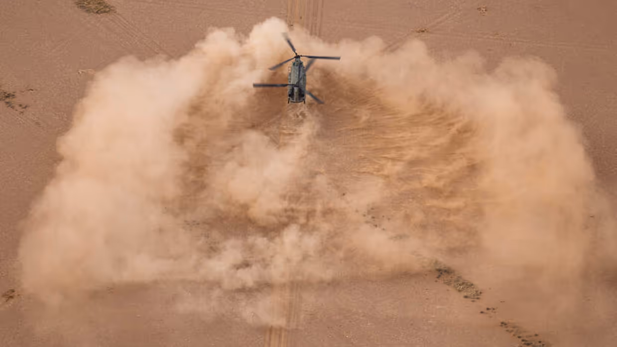 Een helikopter landt in de woestijn.