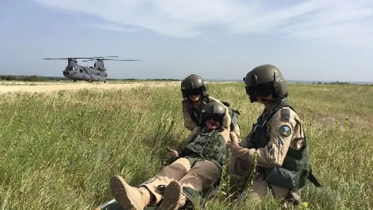 2 militairen helpen een gewonde collega tijdens een oefening.