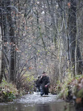 Commando's lopen door water in het bos.
