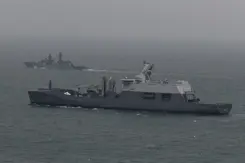 Een marineschip escorteert een ander schip op zee.