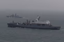 Een marineschip escorteert een ander schip op zee.
