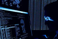 Een man kijkt in het donker naar een computerscherm.