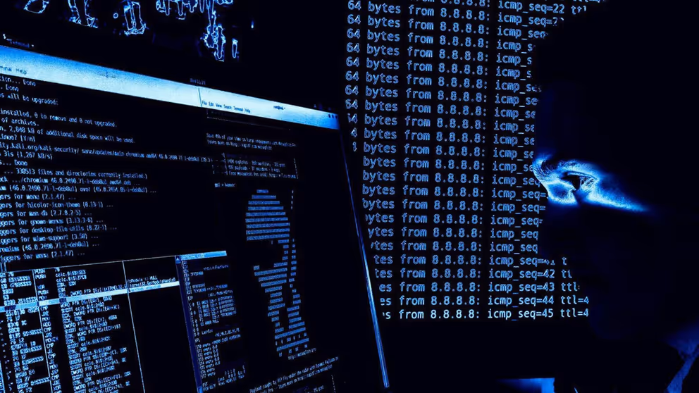 Een man kijkt in het donker naar een computerscherm.