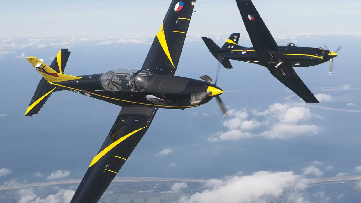 Twee Pilatus PC-7 vliegtuigen voeren een zij aan zij rol uit.