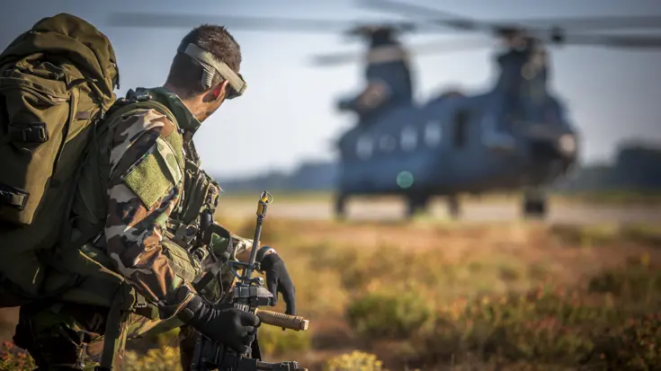 Luchtmobiele militair wacht voordat hij aan boord kan van de Chinook-transporthelikopter op de achtergrond, oefening Hot Blade 2014.