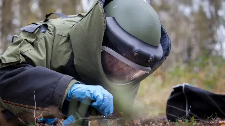 Een explosievenruimer in een bommenpak ontmantelt een oefenexplosief.