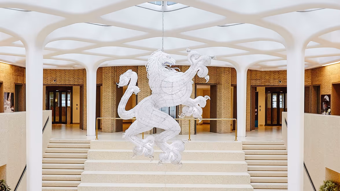 Hal met trappen en grote leeuw als decoratie aan plafond.