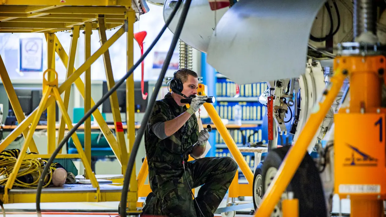 Militair schijnt met zaklamp op de wielophanging van een vliegtuig.