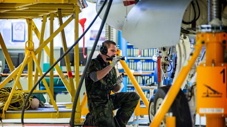 Militair schijnt met zaklamp op de wielophanging van een vliegtuig.