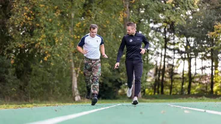 2 mannen lopen op een groene atletiekbaan.