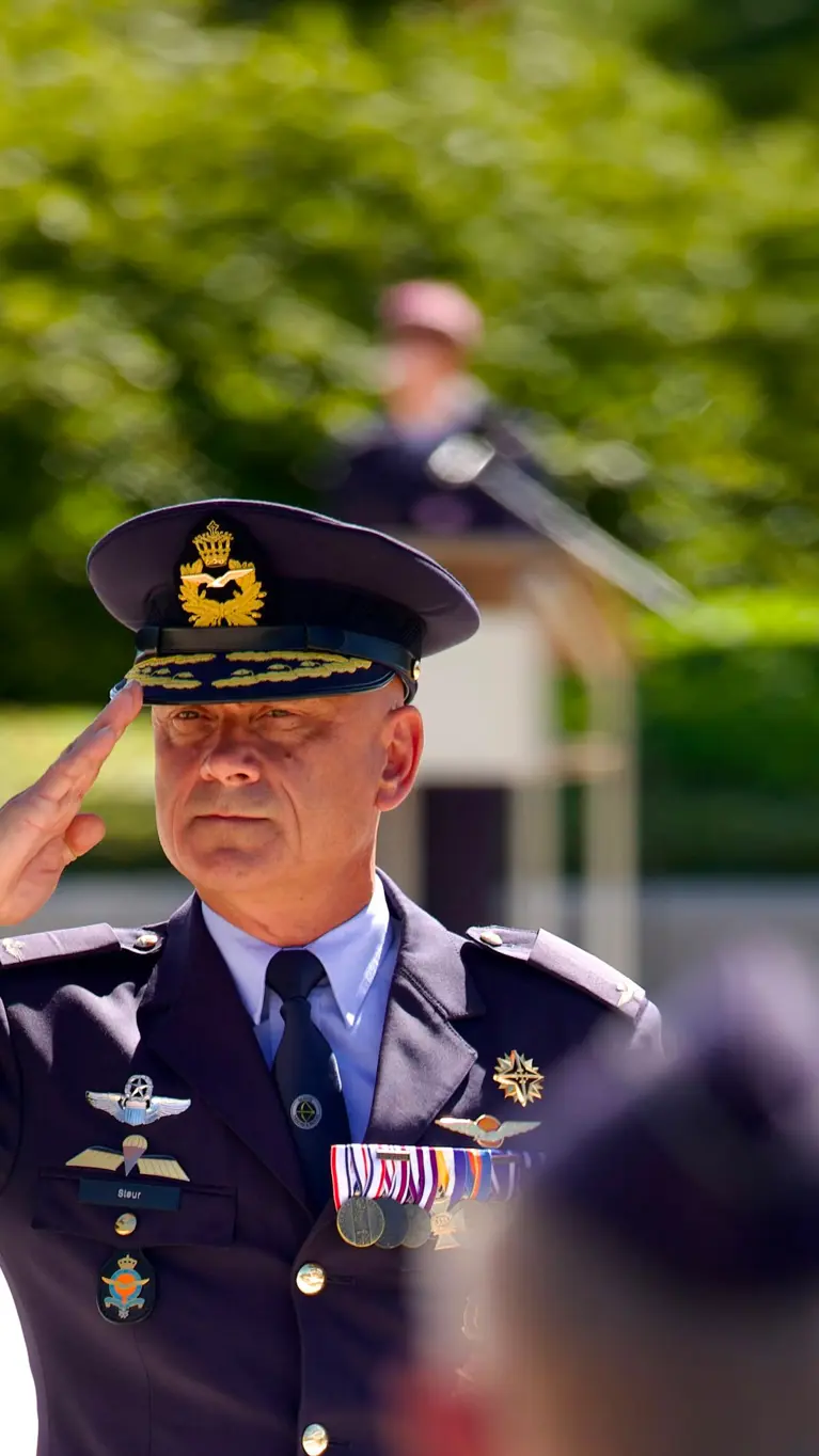 Luitenant-generaal André Steur salueert naar aan aantal militairen die wazig in de voorgrond te zien zijn.