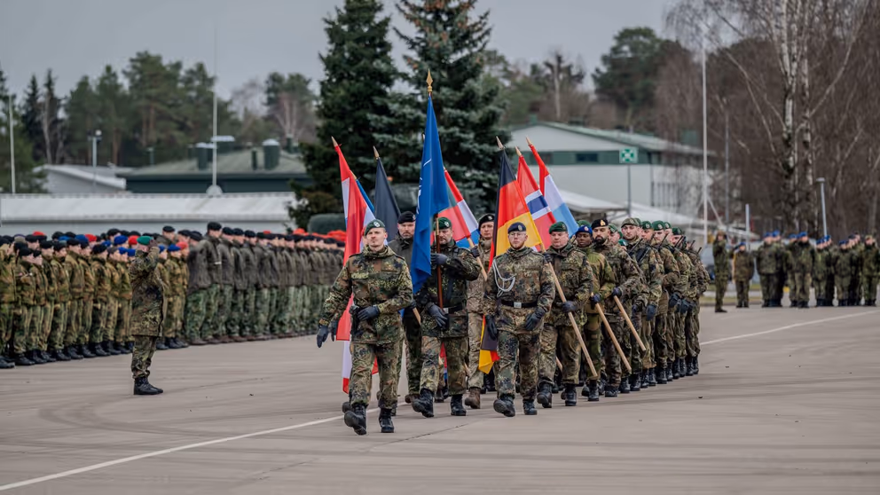 De militairen in Litouwen dragen de vlaggen van de NAVO en de deelnemende landen.