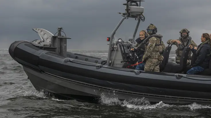 Het snelle vaartuig de FRISC scheert over het wateroppervlak. Aan boord meerdere miilitairen, inclusief een lachende prinses
