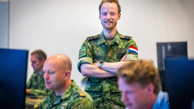 Een militair van de luchtmacht poseert met voor hem twee militairen en een burgermedewerker.